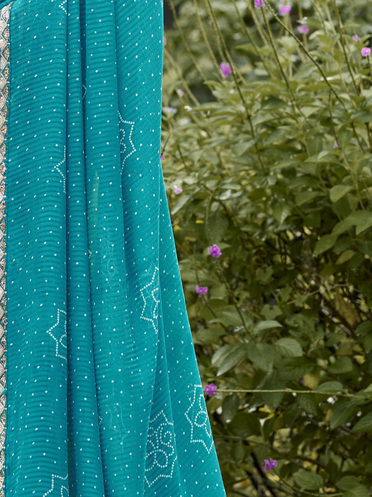 Pallu detail of turquoise blue georgette saree showing bandhani tie-dye dot work and zari border
