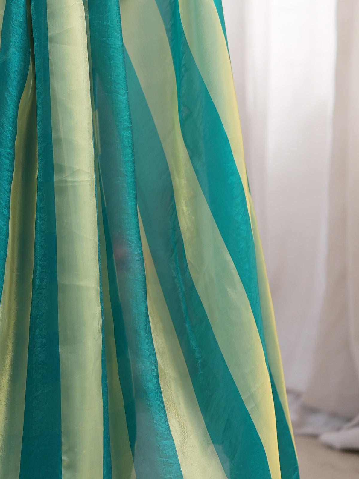 Pallu detail of teal green satin saree showing striped pattern design and embroidered border