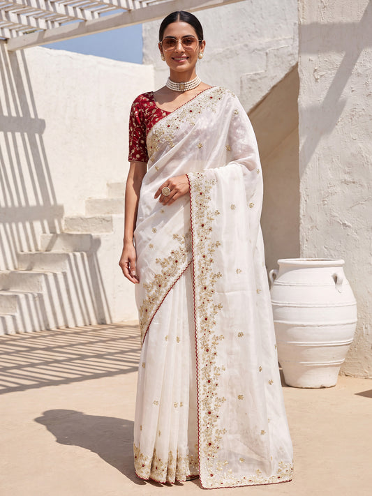 Woman wearing white satin saree with ornamented surface design and maroon blouse