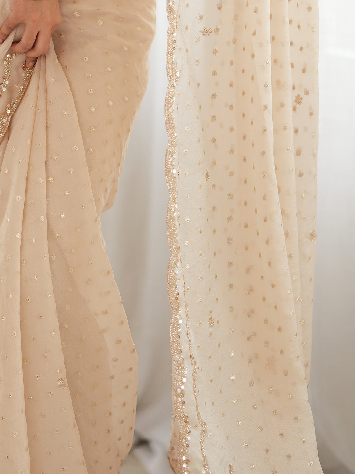 Pallu detail of cream georgette saree showing zari butta (metallic motif) work and embellished border