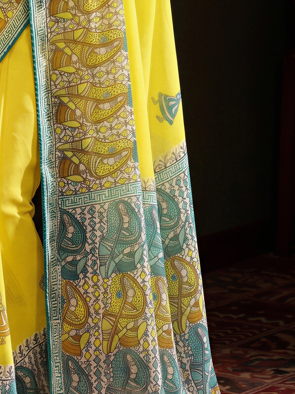 Pallu detail of yellow georgette saree showing traditional indian print motifs and embroidered border