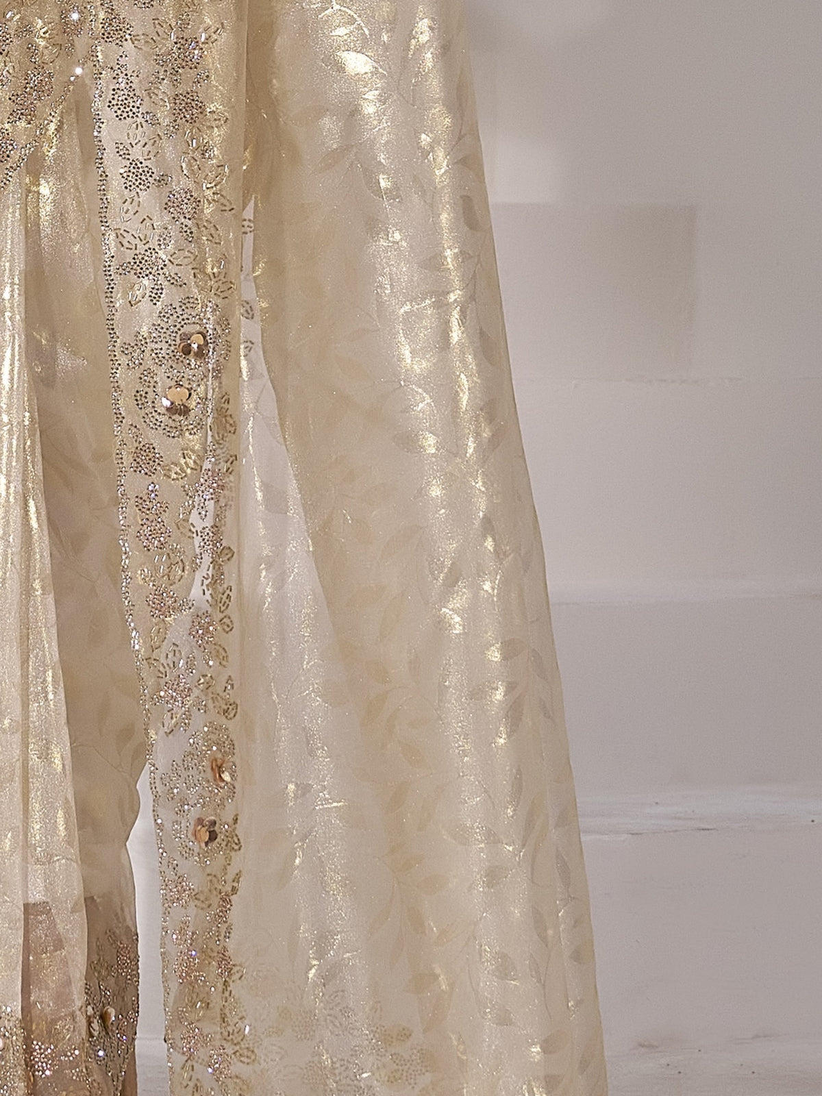 Pallu detail of cream organza saree showing applique design and scallop border