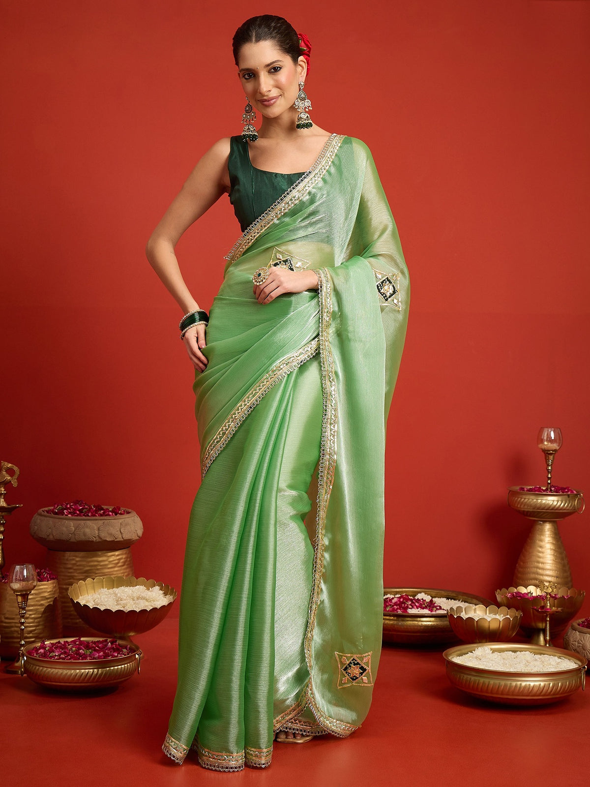 Woman wearing sea green paper silk saree with ornamented surface design and green blouse
