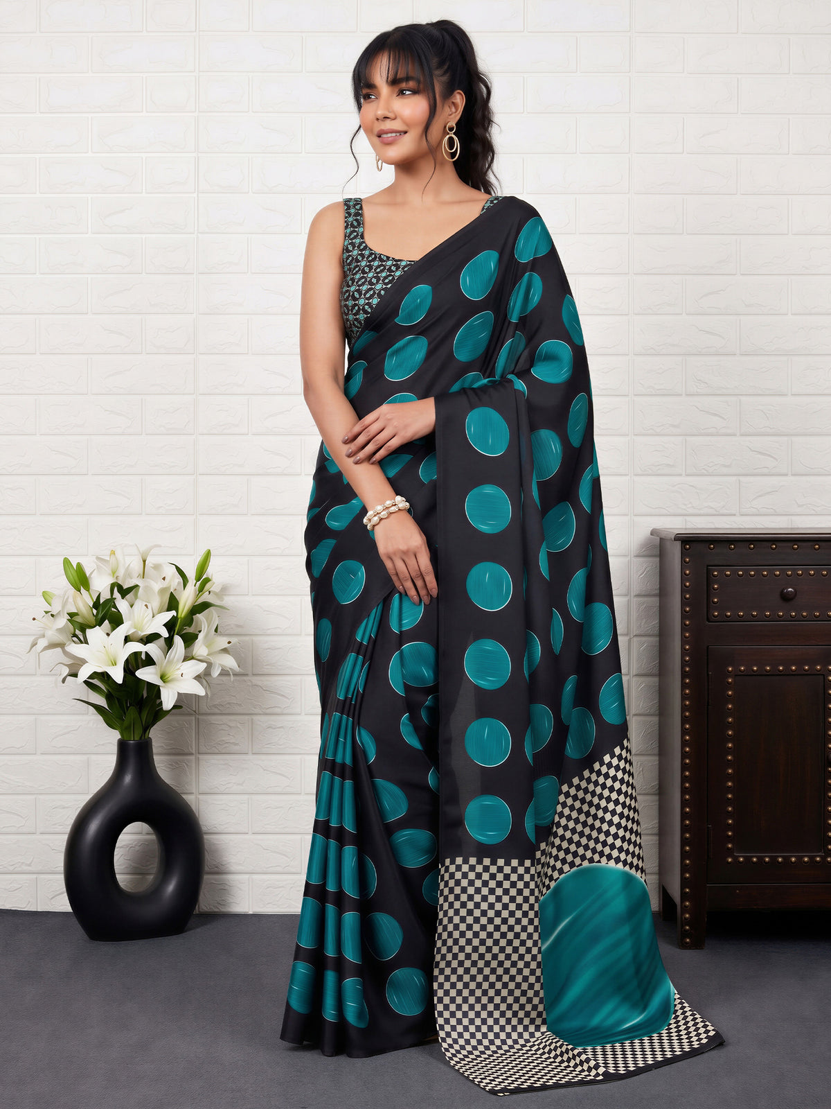 Woman wearing teal blue satin saree with traditional indian motif work and black blouse