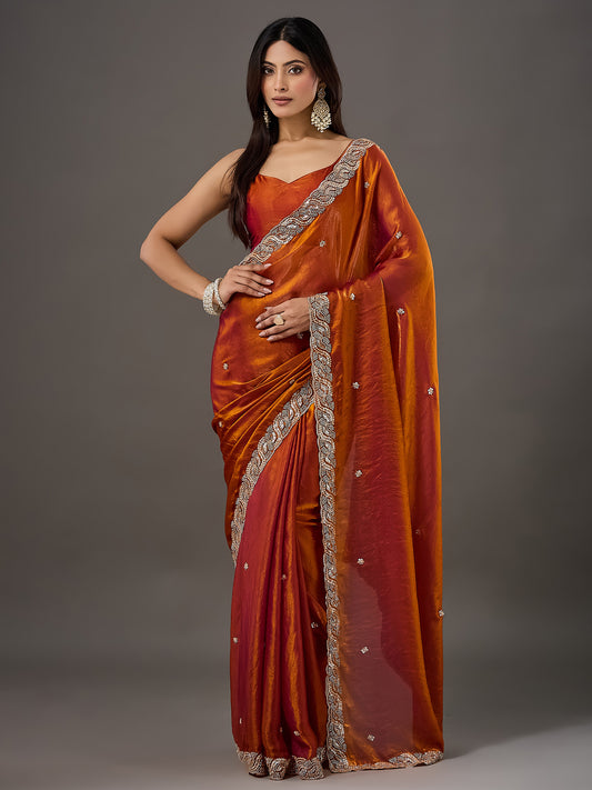 Woman wearing orange satin saree with ornamented surface design and orange blouse