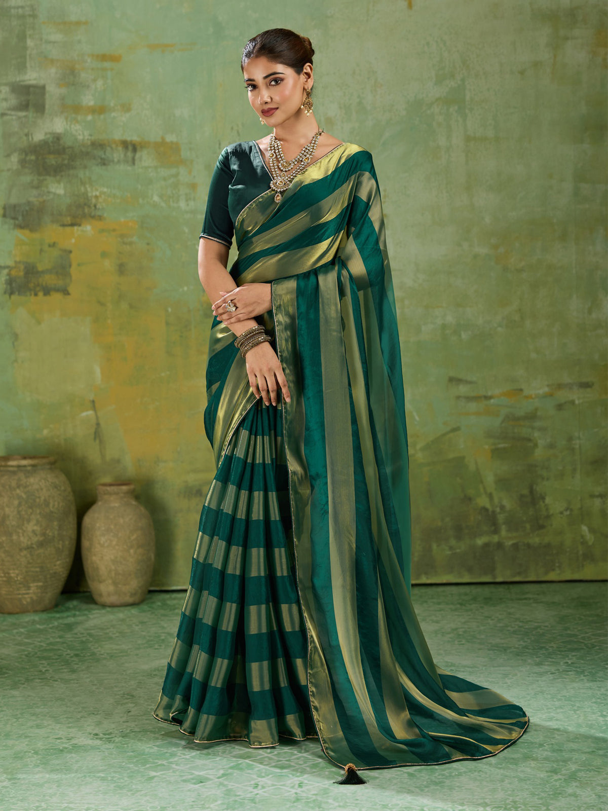 Woman wearing teal green satin silk saree with colour-blocked design and teal green blouse