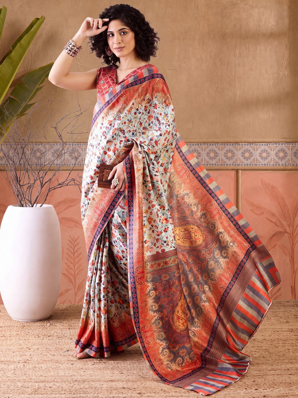 Woman wearing sea green poly silk saree with paisley (kairi) motif work and orange blouse
