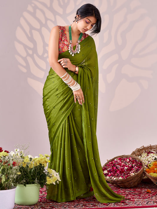 Woman wearing green chiffon saree with ornamented surface design and rust blouse