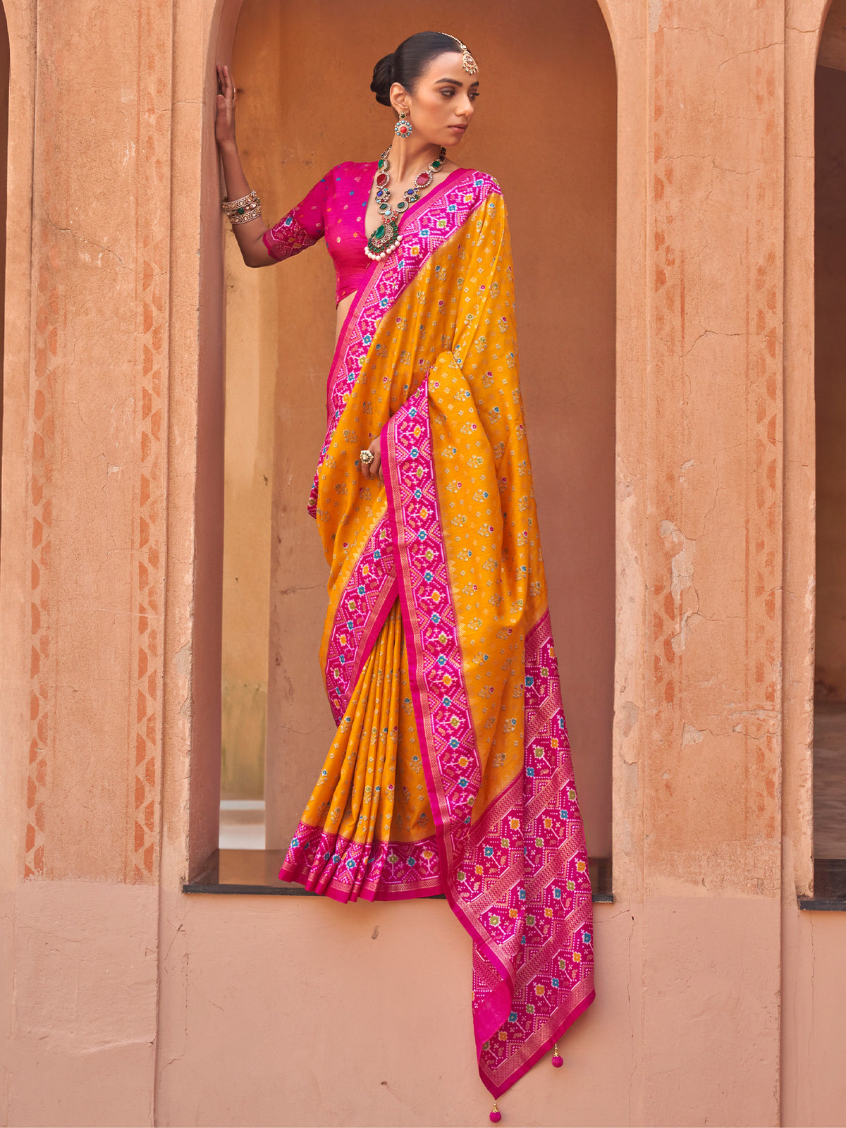 Woman wearing mustard silk blend saree with ikat resist-dyed pattern and pink blouse