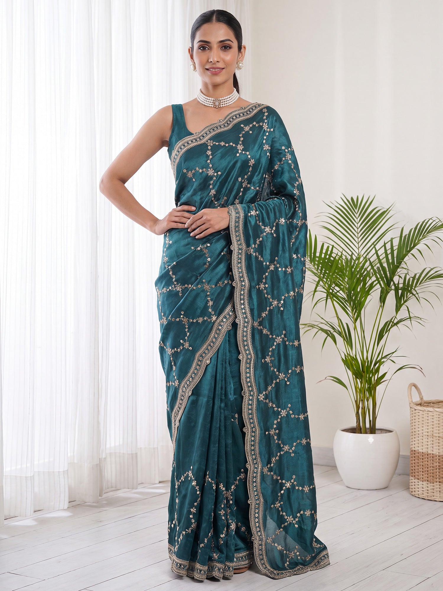 Woman wearing teal green satin saree with embroidered motif work and teal green blouse