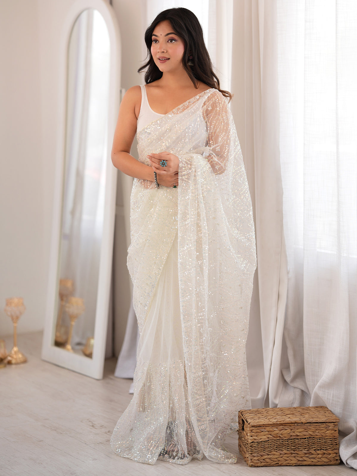 Woman wearing white net saree with ornamented surface design and white blouse