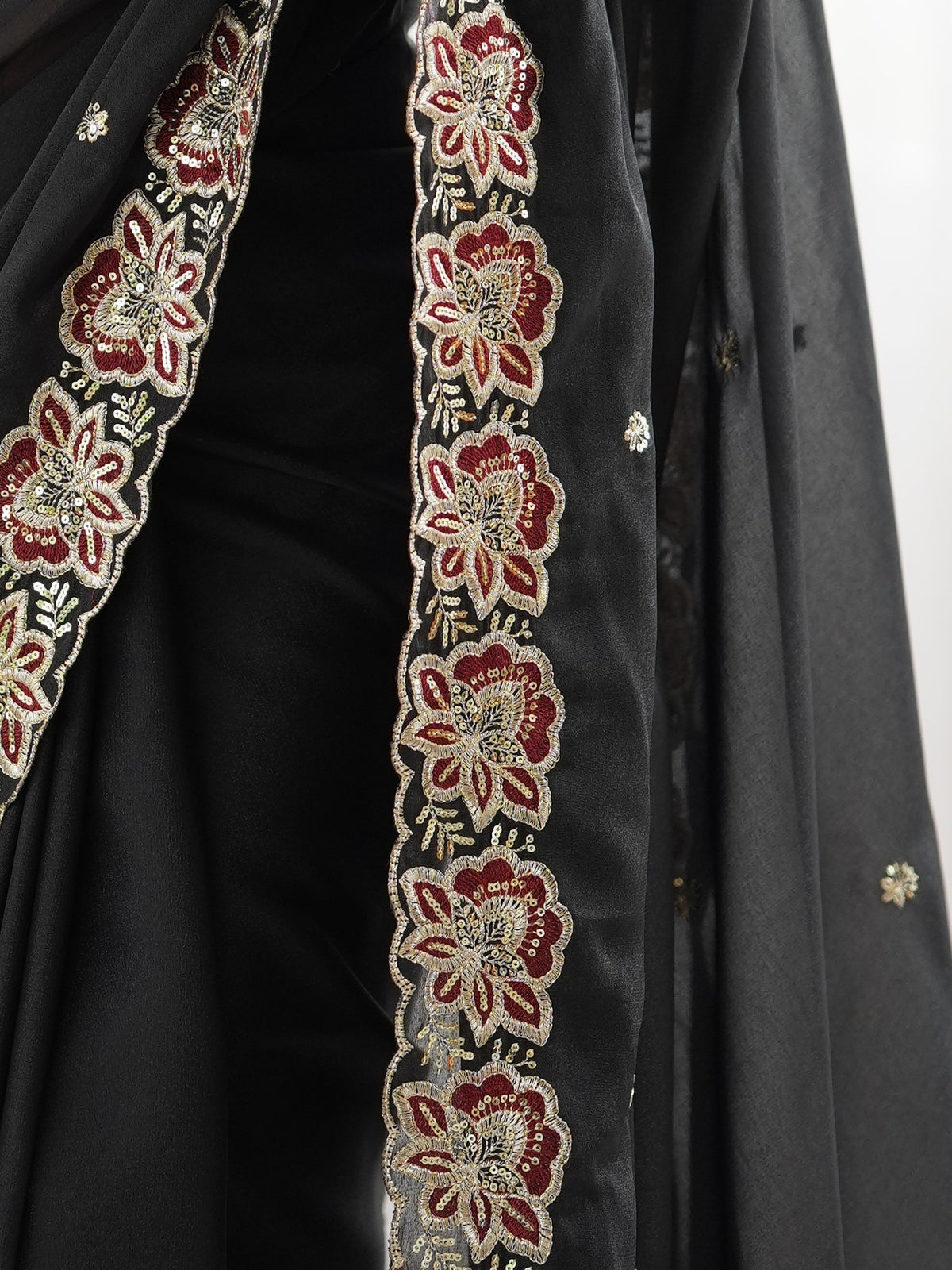 Pallu detail of black georgette saree showing ornamented surface design and embellished border