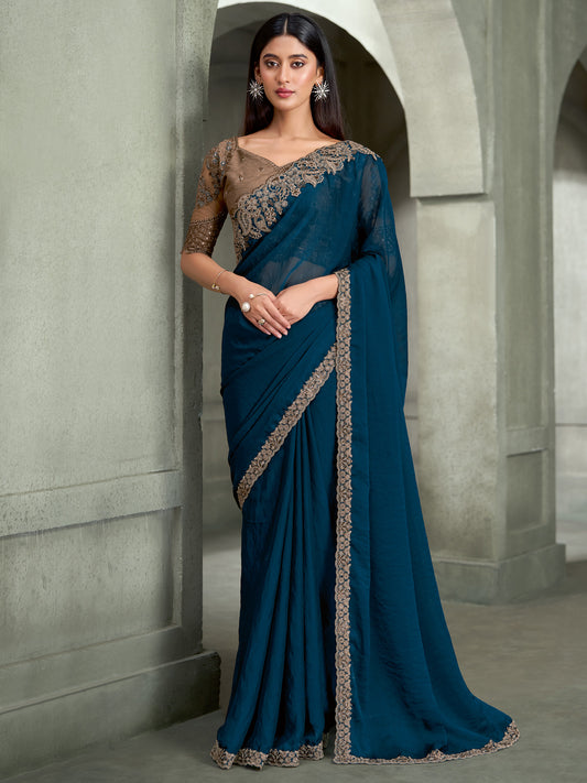 Woman wearing teal blue georgette saree with embroidered motif work and grey blouse