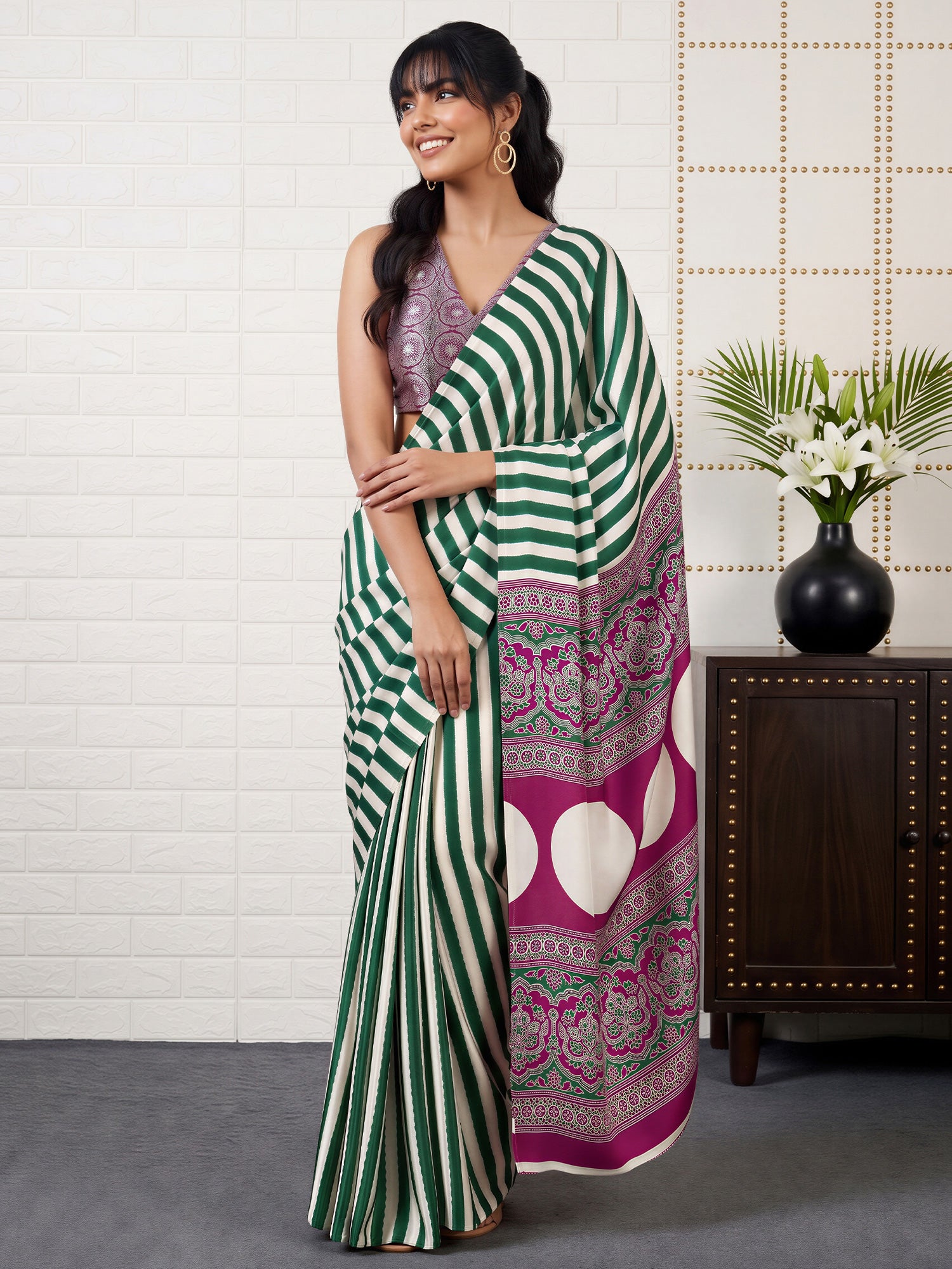 Woman wearing green satin saree with striped pattern design and magenta blouse
