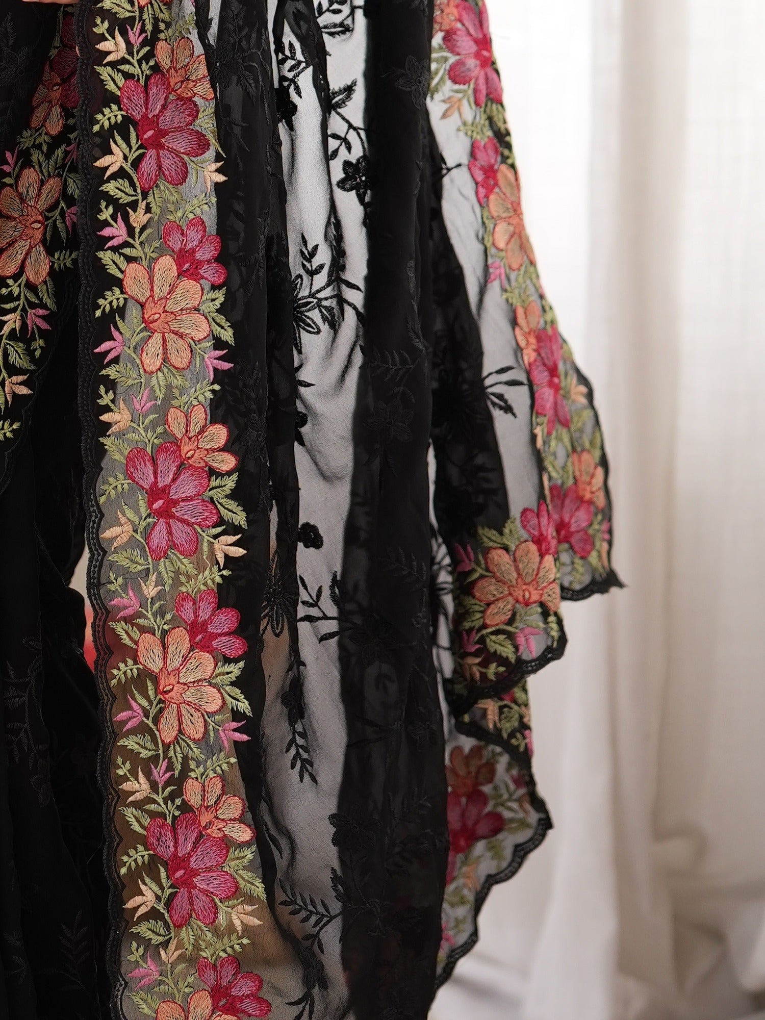 Pallu detail of black georgette saree showing all-over floral design and embroidered border