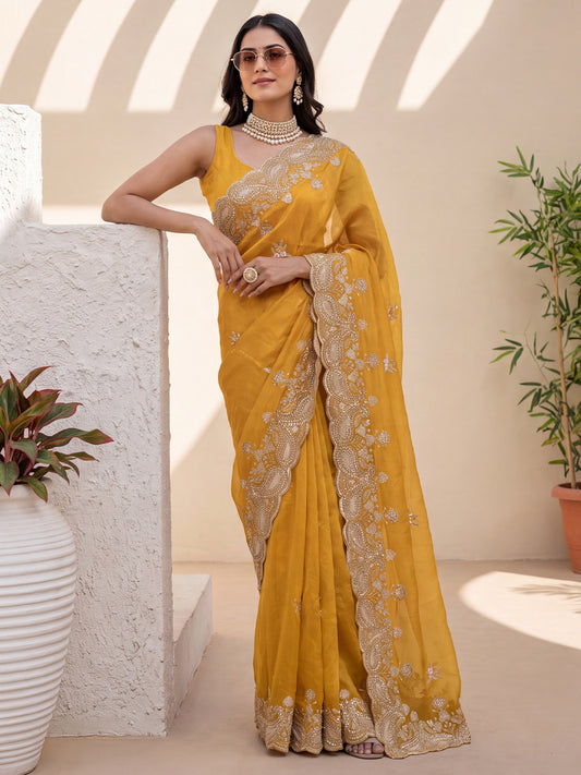 Woman wearing mustard satin saree with embroidered motif work and mustard blouse