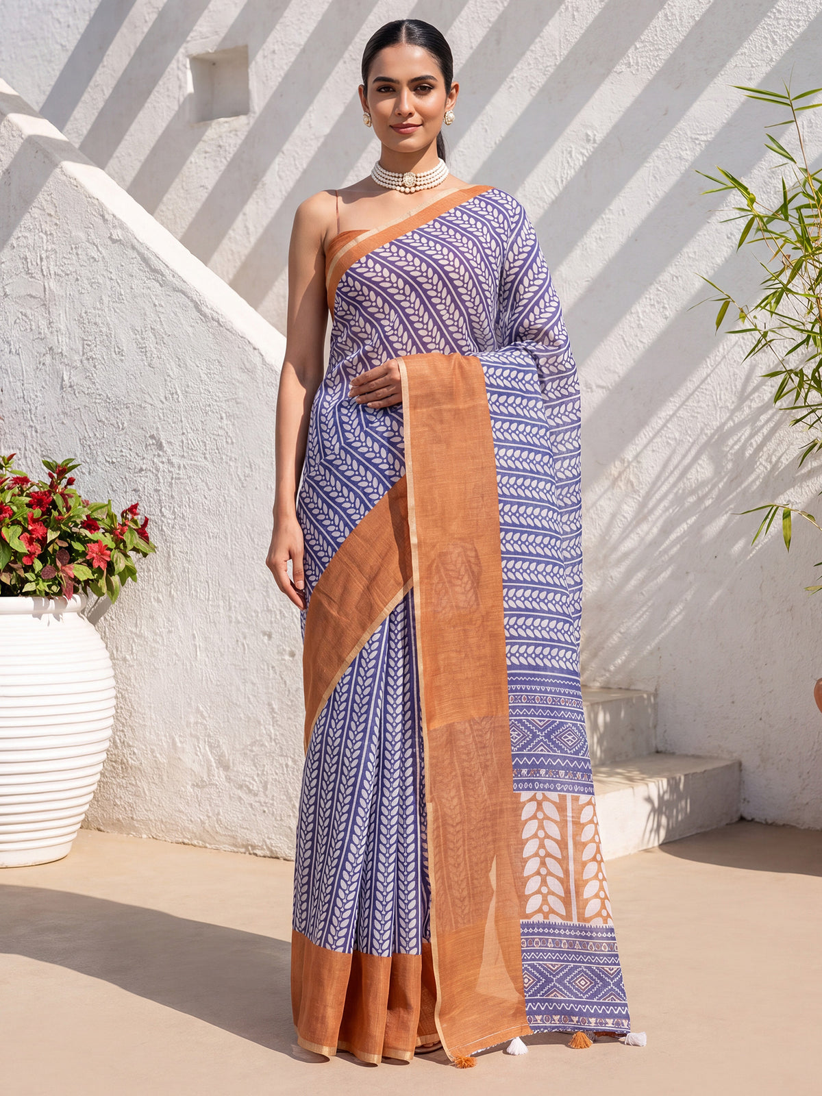 Woman wearing blue cotton linen saree with geometric pattern design and rust blouse