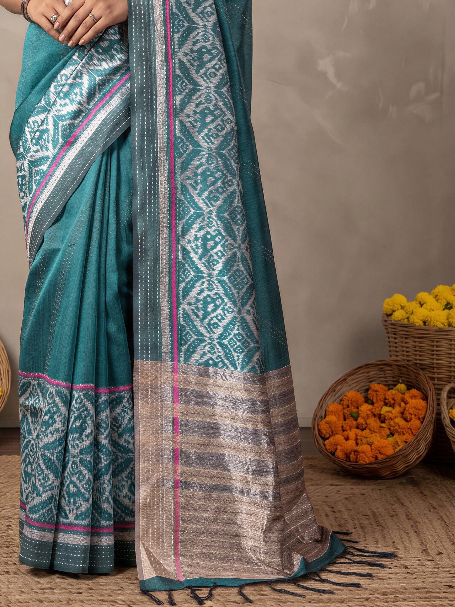 Pallu detail of teal blue silk cotton saree showing ikat resist-dyed pattern and embroidered border