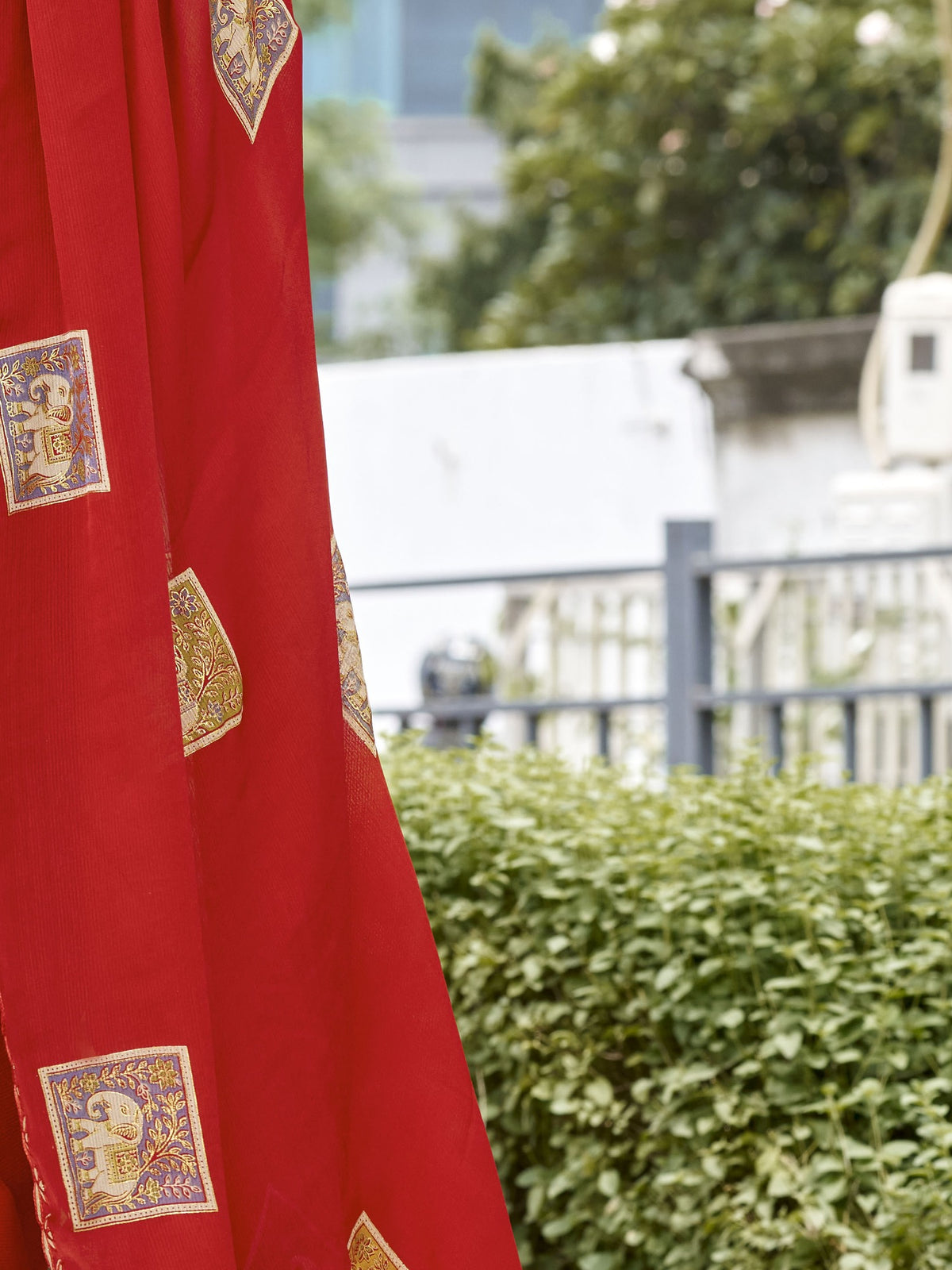 Pallu detail of red chiffon saree showing metallic foil print work and embellished border