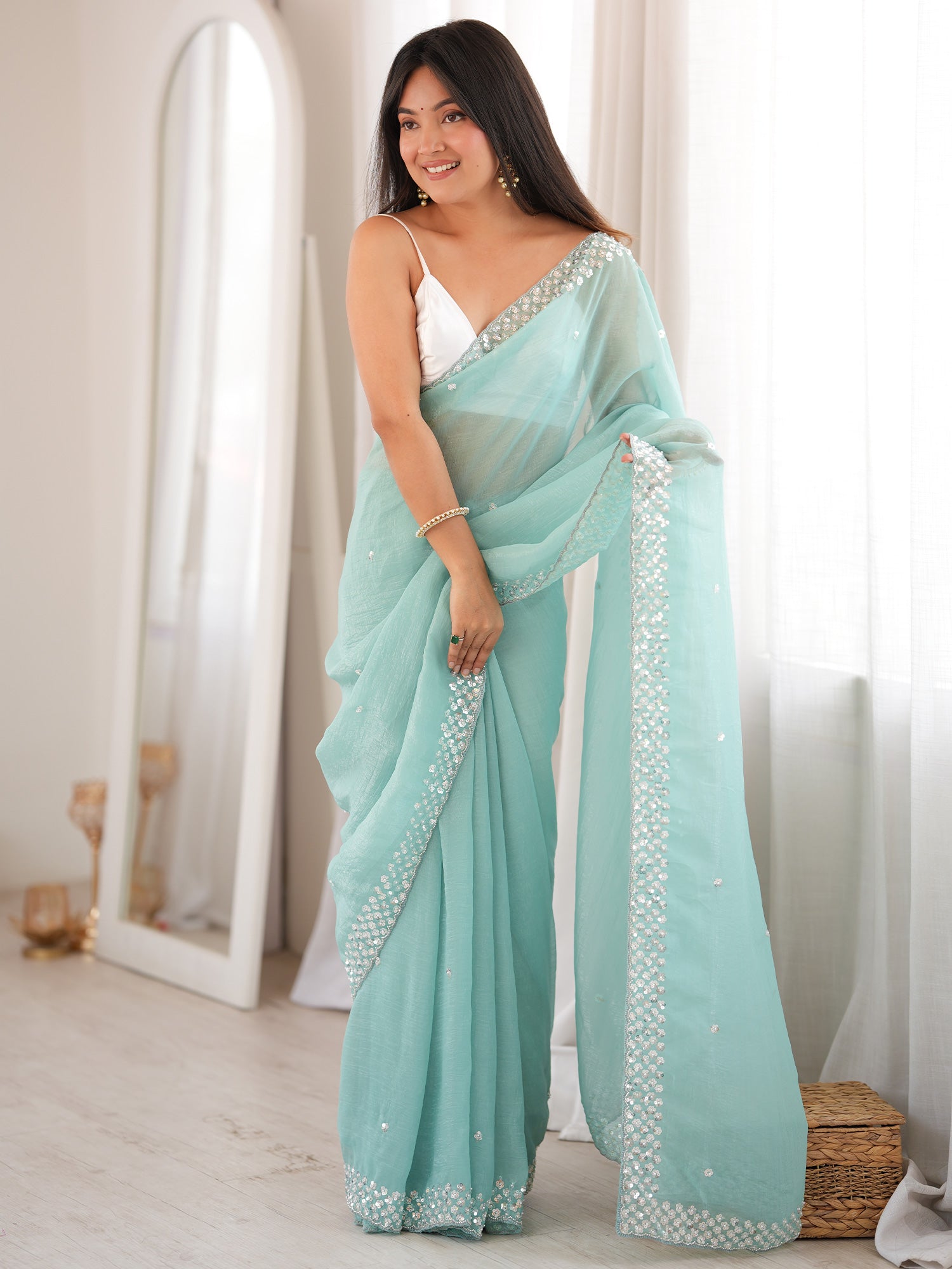 Woman wearing light blue georgette saree with embroidered motif work and white blouse