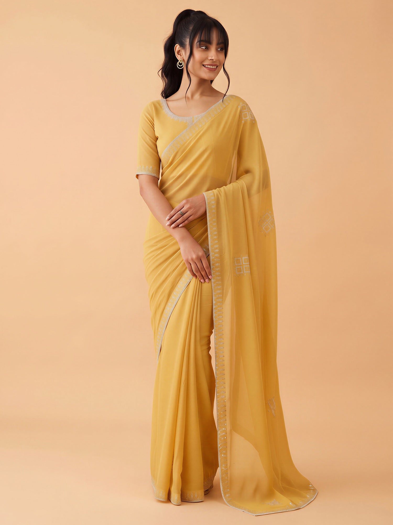 Woman wearing yellow georgette saree with ornamented surface design and yellow blouse