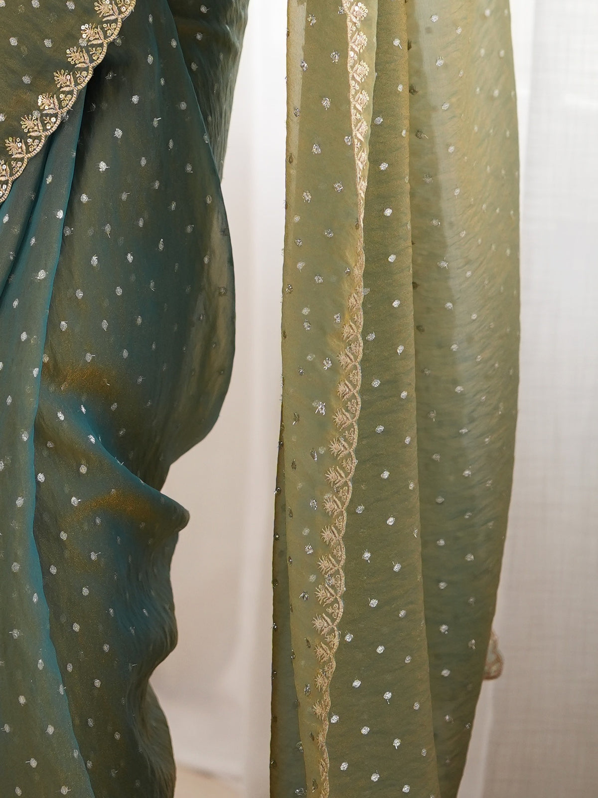 Pallu detail of olive georgette saree showing zari butta (metallic motif) work and embellished border