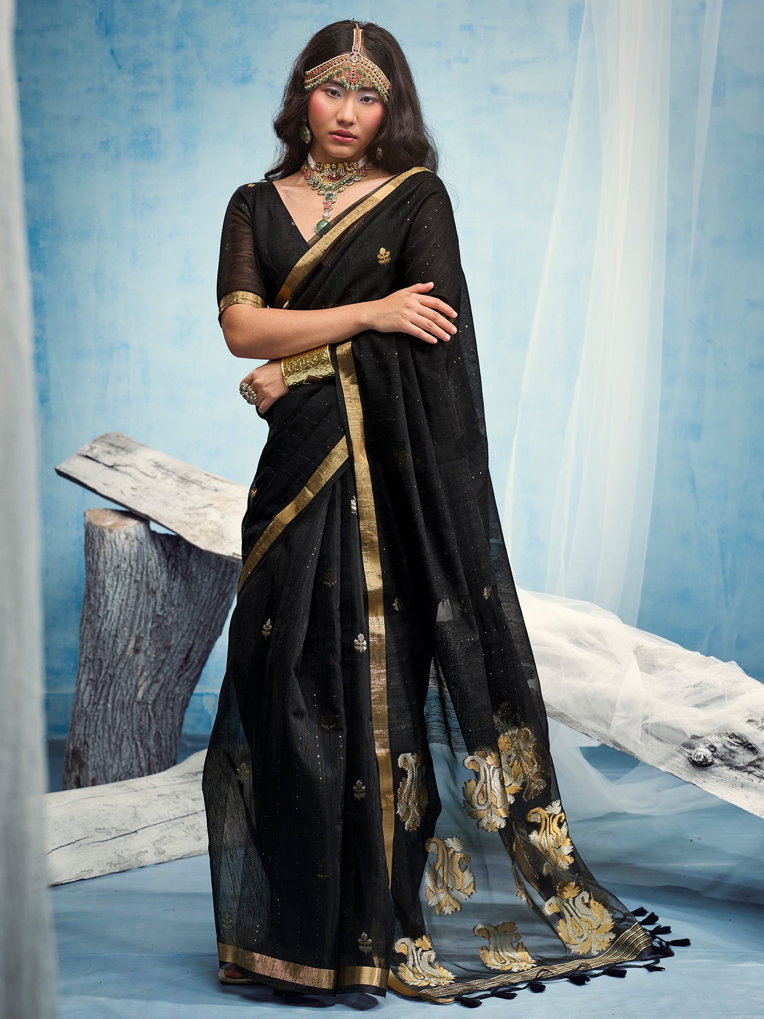 Woman wearing black muga silk saree with zari butta (metallic motif) work and black blouse