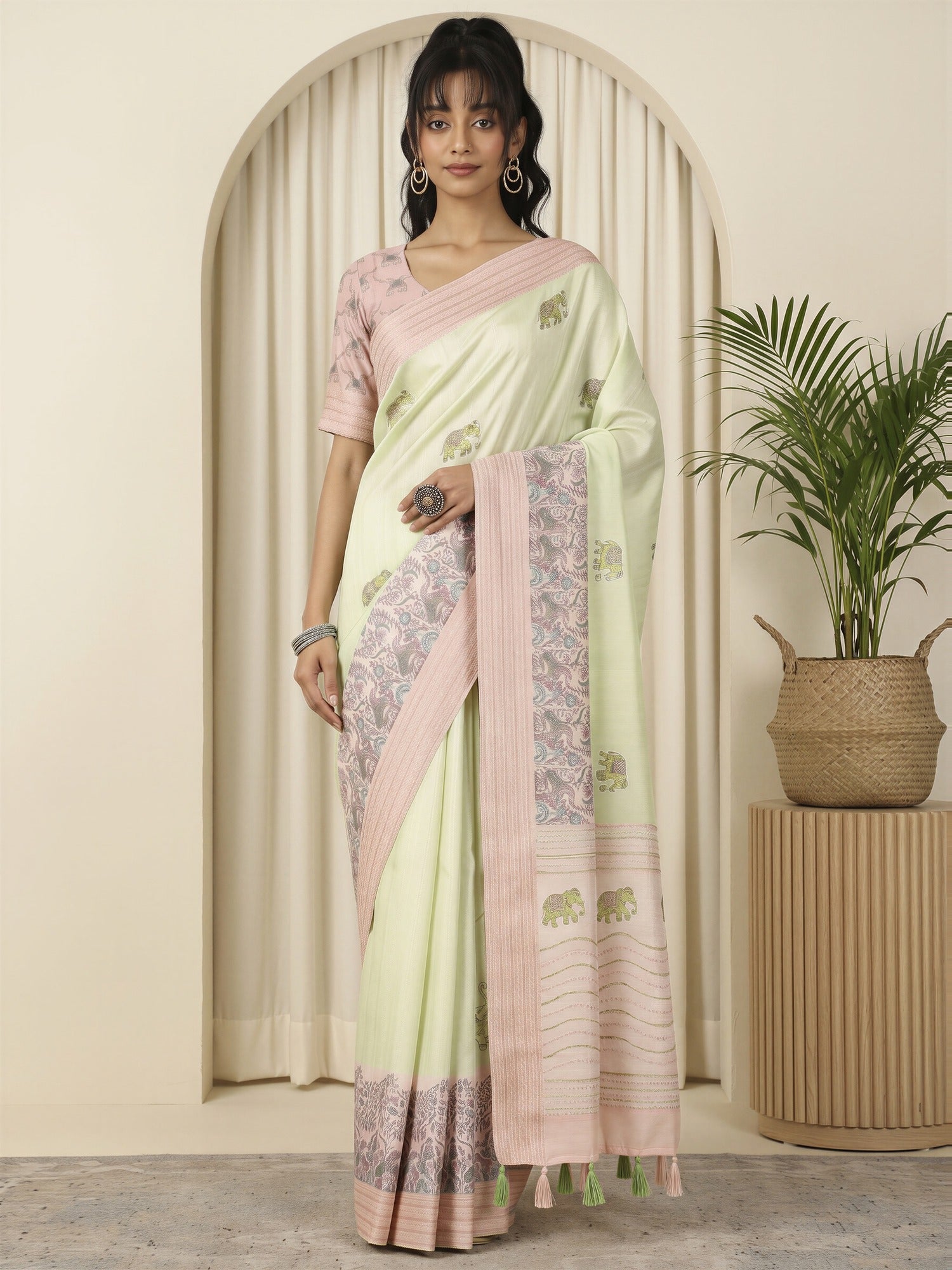 Woman wearing light green silk blend saree with traditional indian motif work and pink blouse