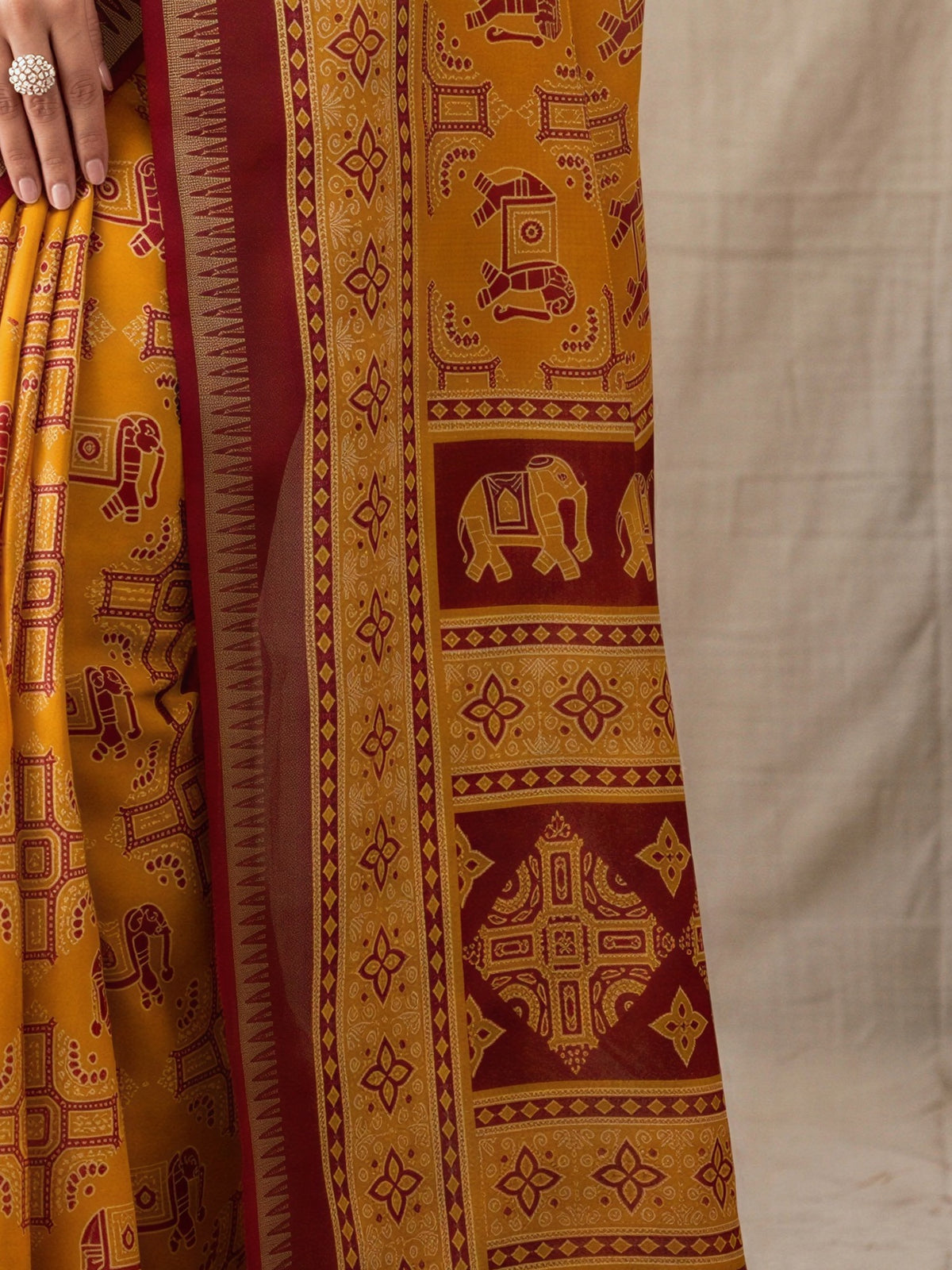 Pallu detail of mustard georgette saree showing traditional indian motif work and zari border