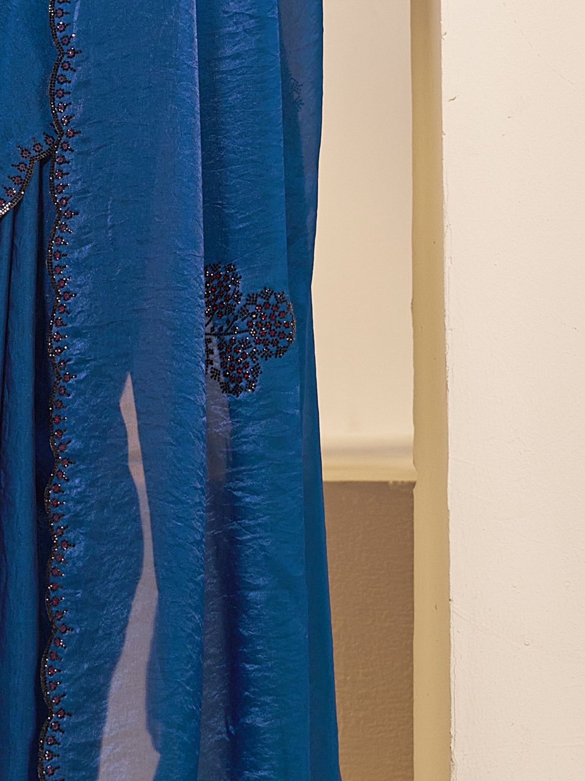 Pallu detail of teal blue satin silk saree showing ornamented surface design and embellished border