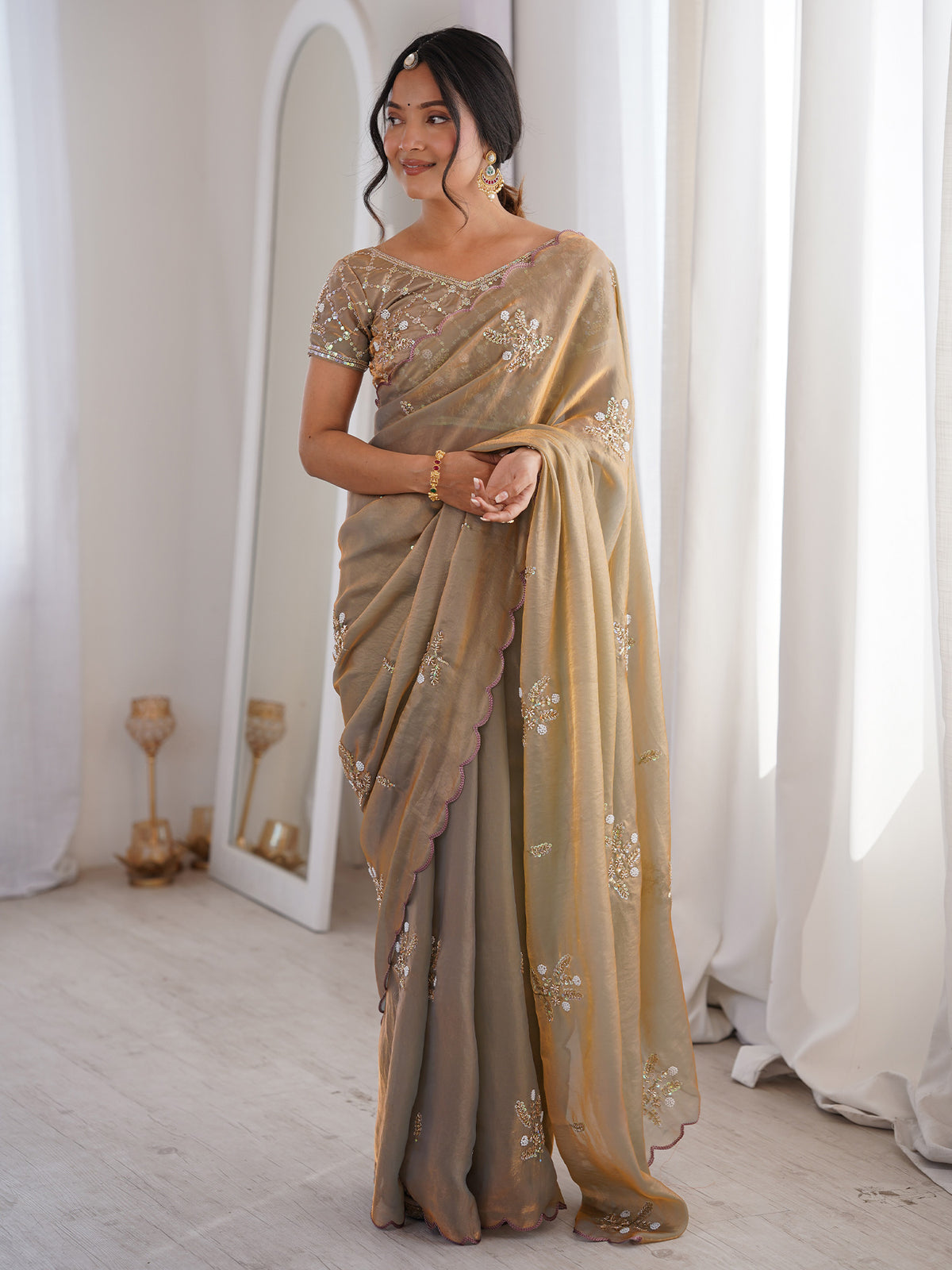 Woman wearing metallic satin saree with ornamented surface design and metallic blouse