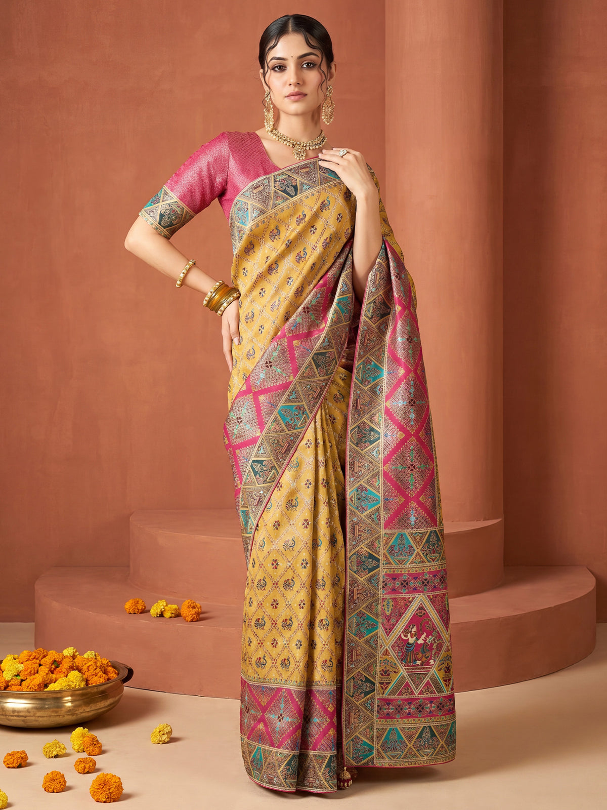 Woman wearing mustard viscose silk saree with traditional indian motif work and pink blouse