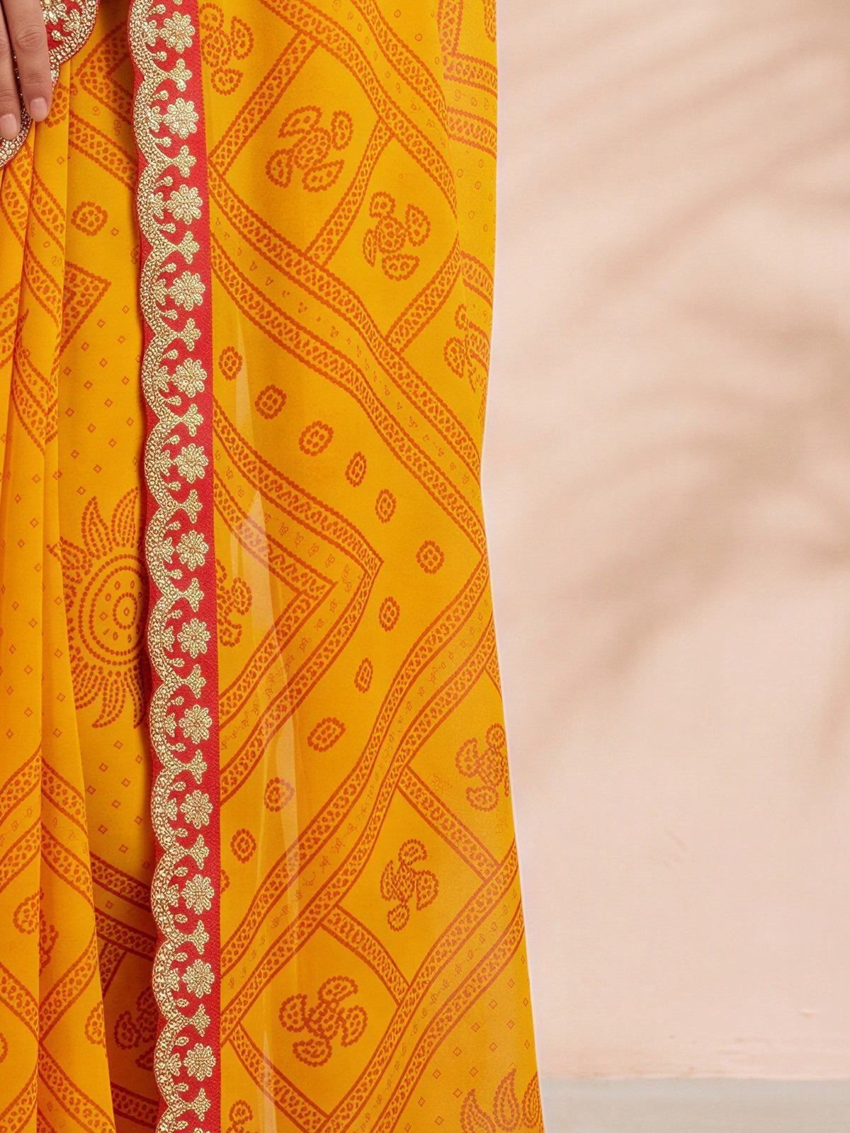 Pallu detail of yellow georgette saree showing bandhani tie-dye dot work and embellished border