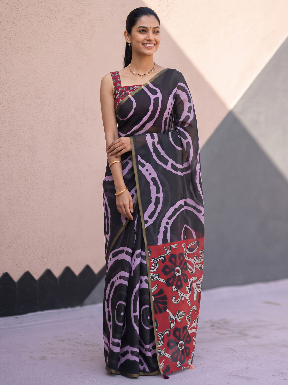 Woman wearing black cotton blend saree with shibori resist-dye pattern and red blouse