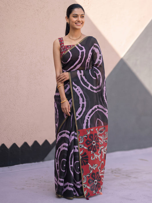 Woman wearing black cotton blend saree with shibori resist-dye pattern and red blouse