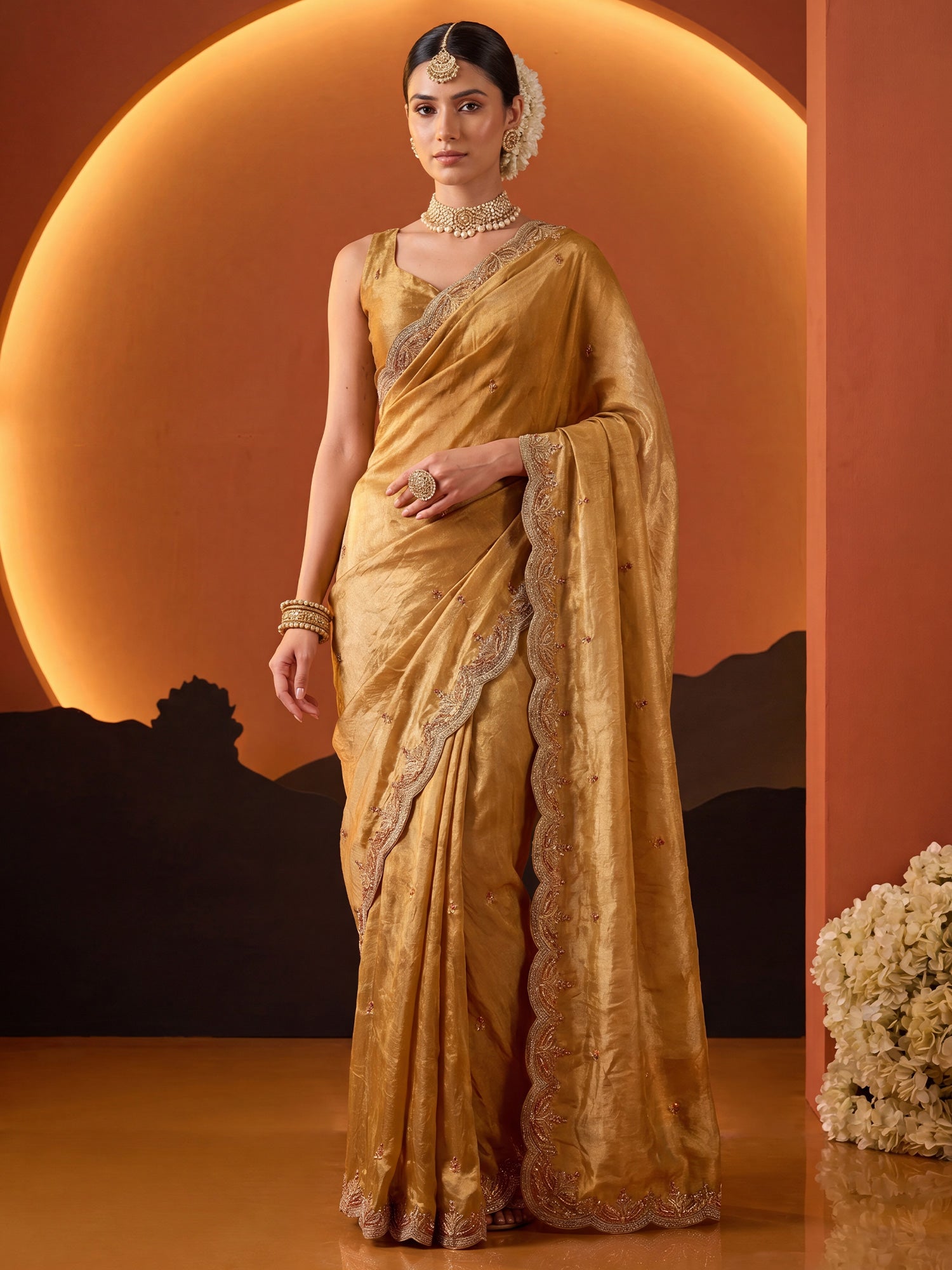 Woman wearing mustard satin saree with ornamented surface design and mustard blouse