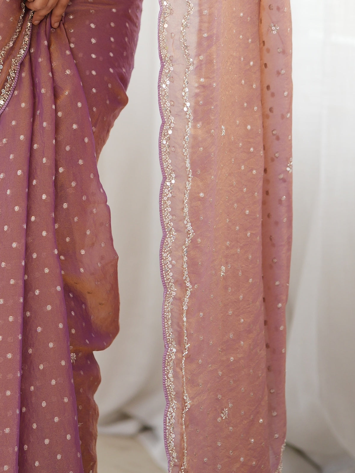 Pallu detail of mauve georgette saree showing zari butta (metallic motif) work and embellished border
