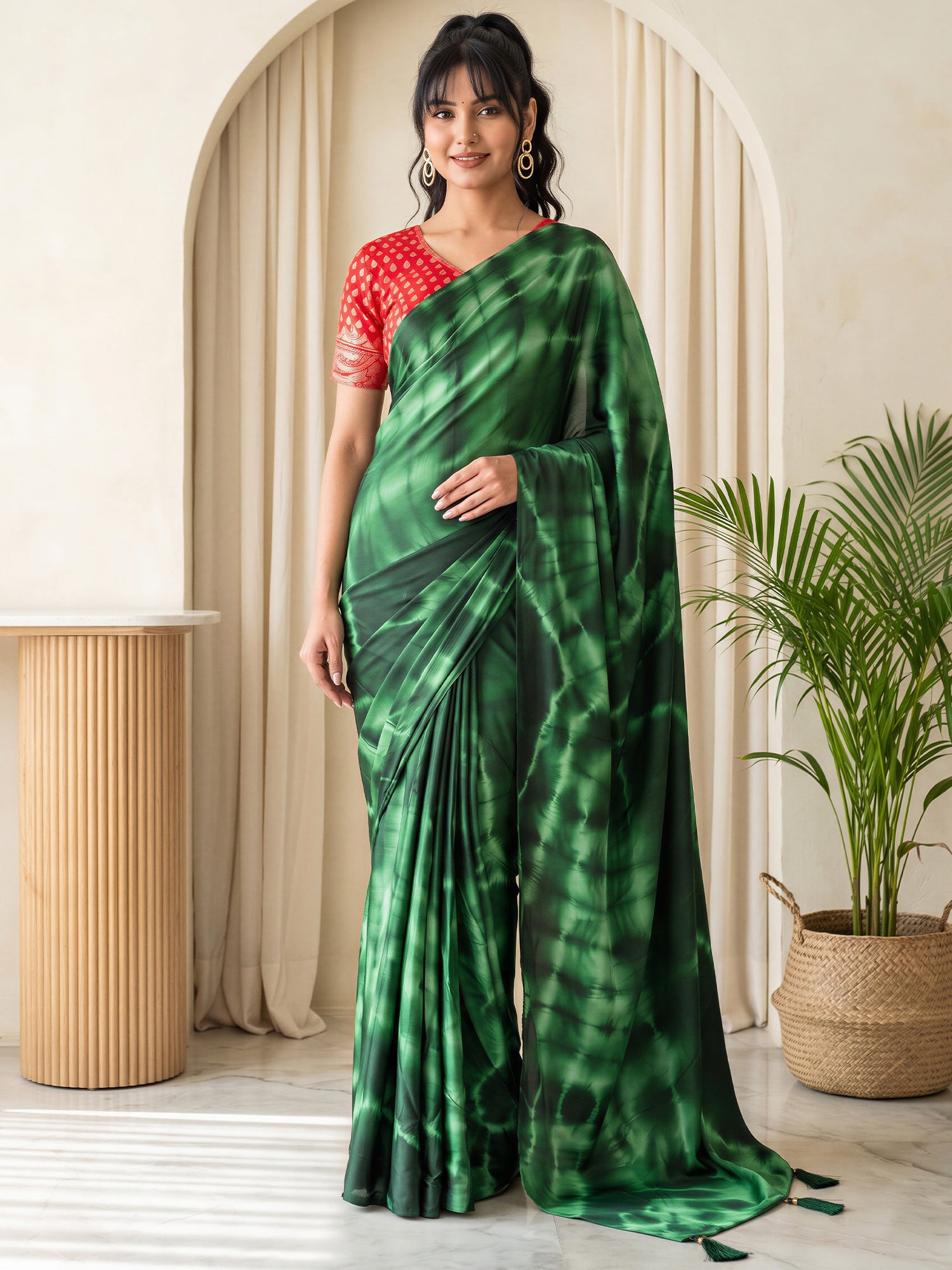 Woman wearing green satin silk saree with tie-and-dye resist pattern and red blouse