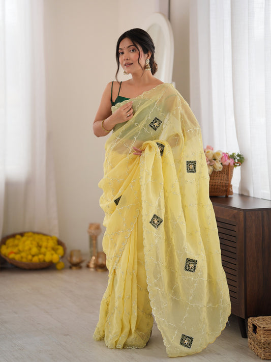 Woman wearing yellow paper silk saree with ornamented surface design and green blouse