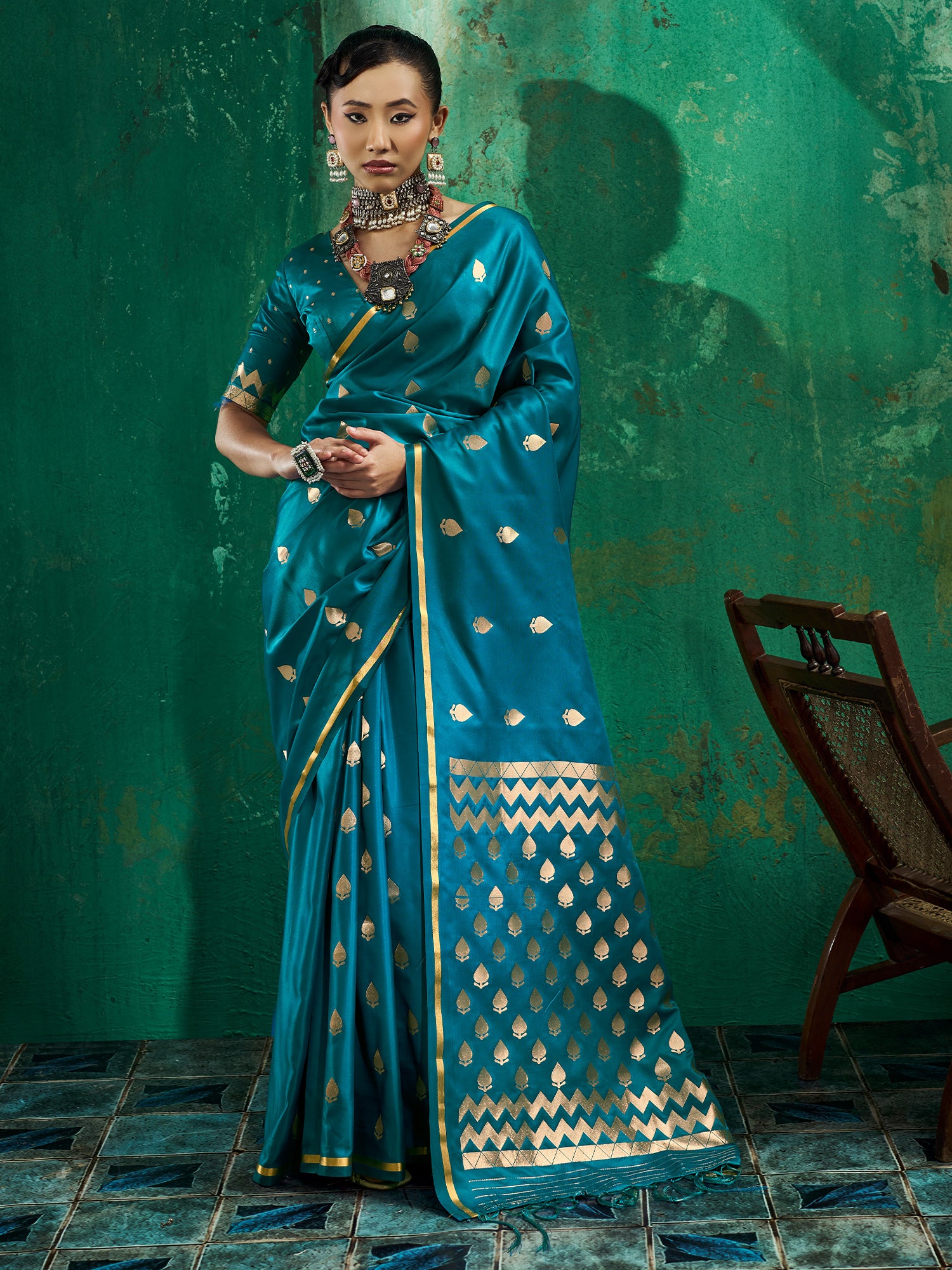 Woman wearing teal blue satin silk saree with zari butta (metallic motif) work and teal blue blouse