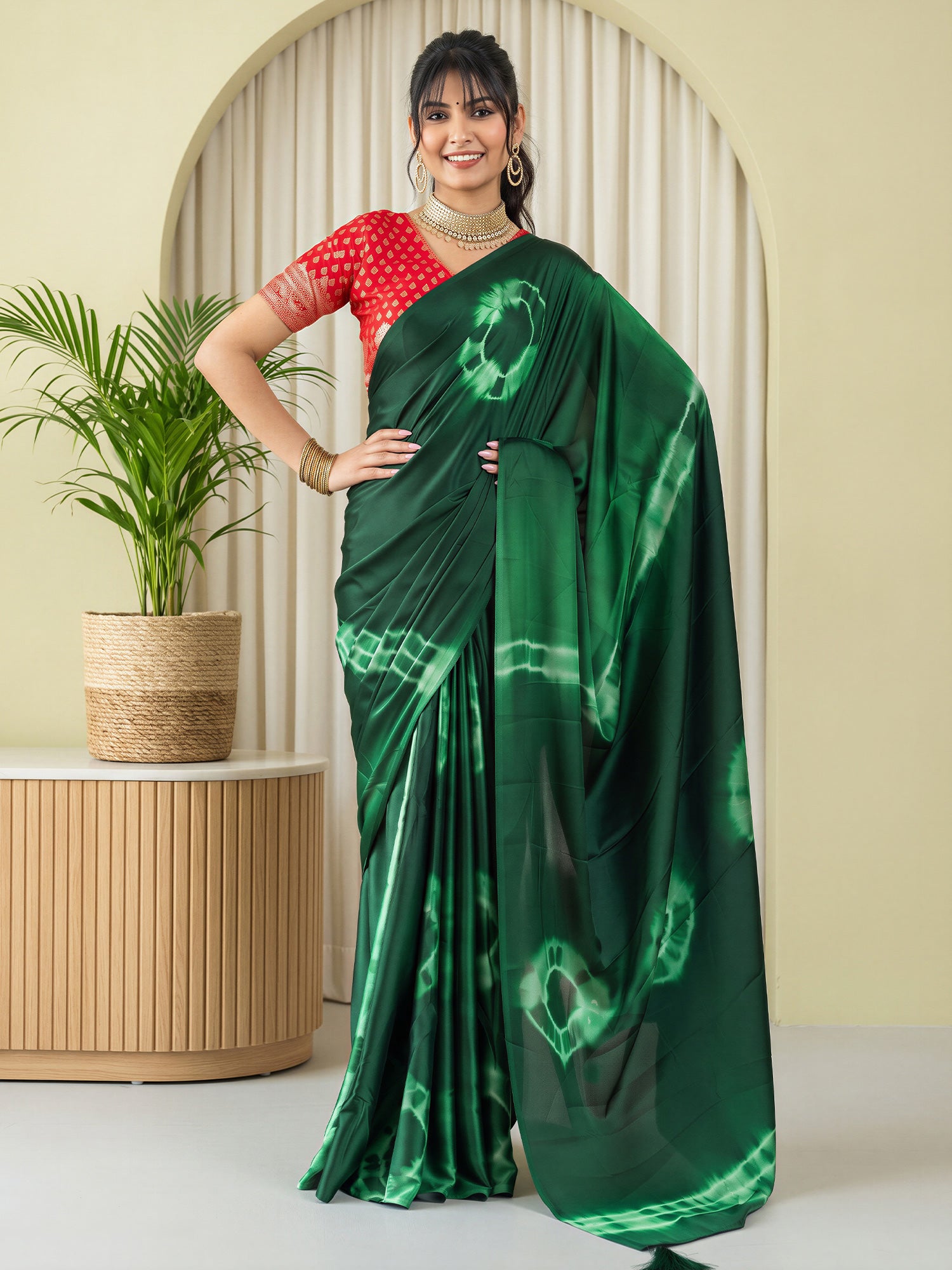 Woman wearing green satin silk saree with tie-and-dye resist pattern and red blouse