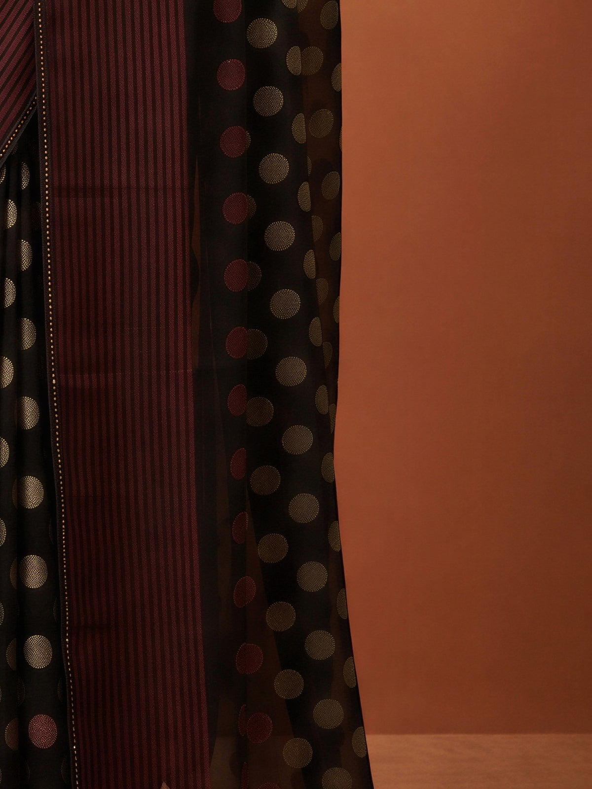 Pallu detail of black georgette saree showing metallic foil print work and embellished border