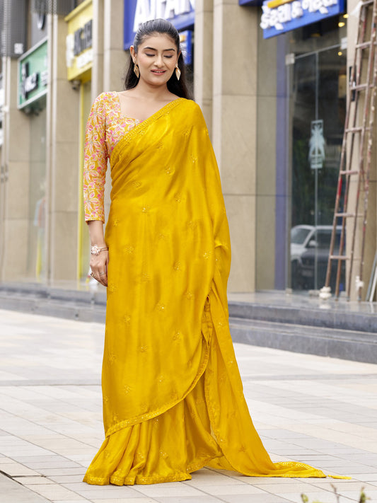 Woman wearing yellow satin silk saree with ornamented surface design and yellow blouse