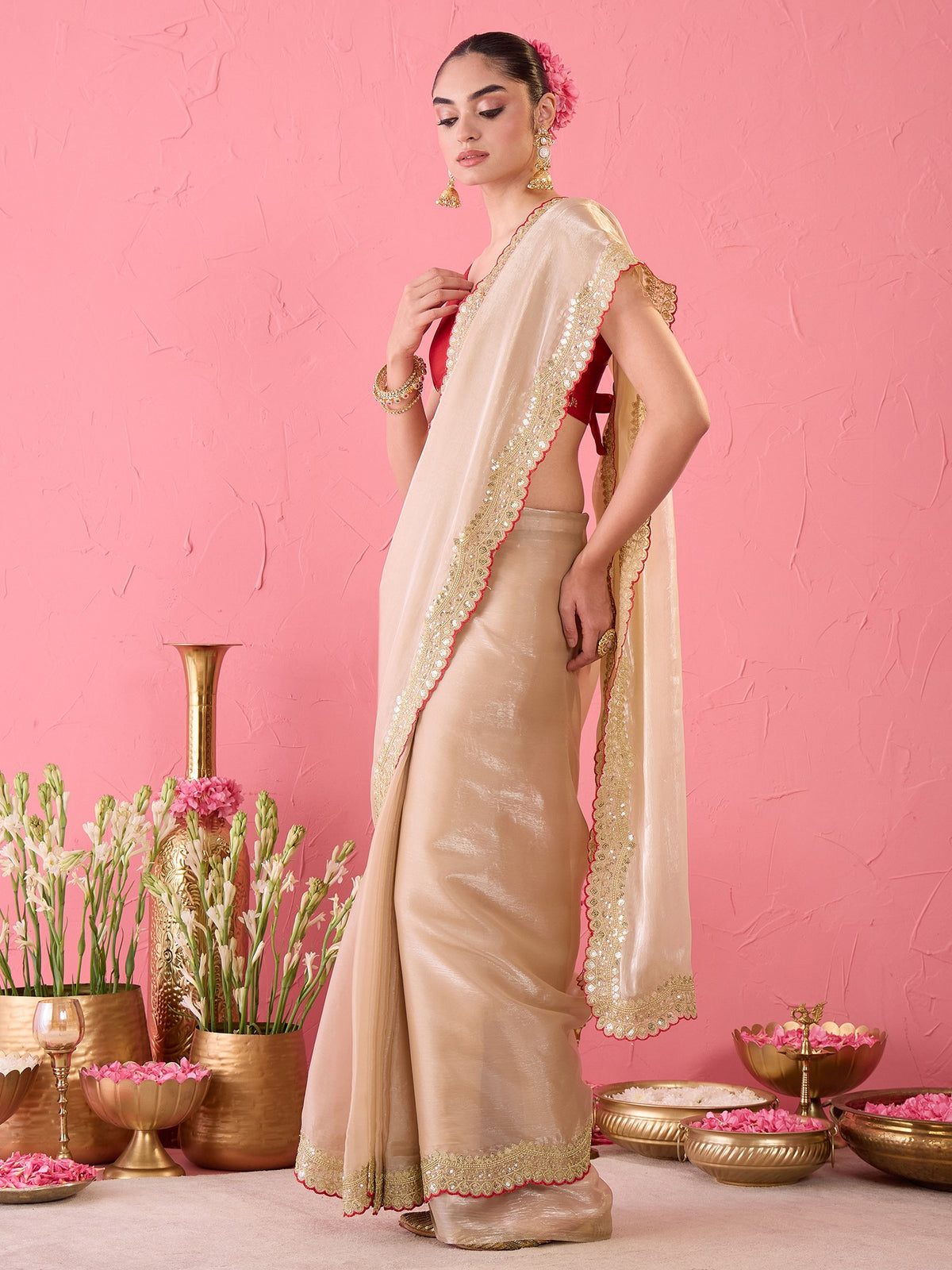 Woman wearing beige satin ready to wear saree with ornamented surface design and red blouse
