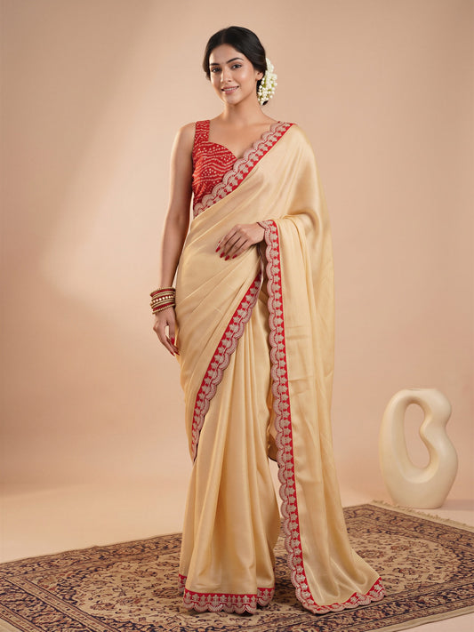 Woman wearing cream satin saree with clean solid-tone finish and red blouse