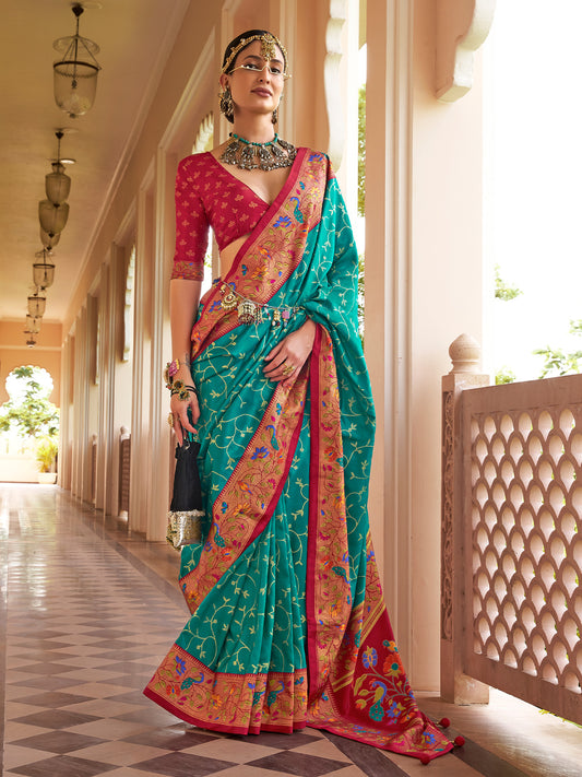 Woman wearing turquoise silk blend saree with all-over floral design and red blouse