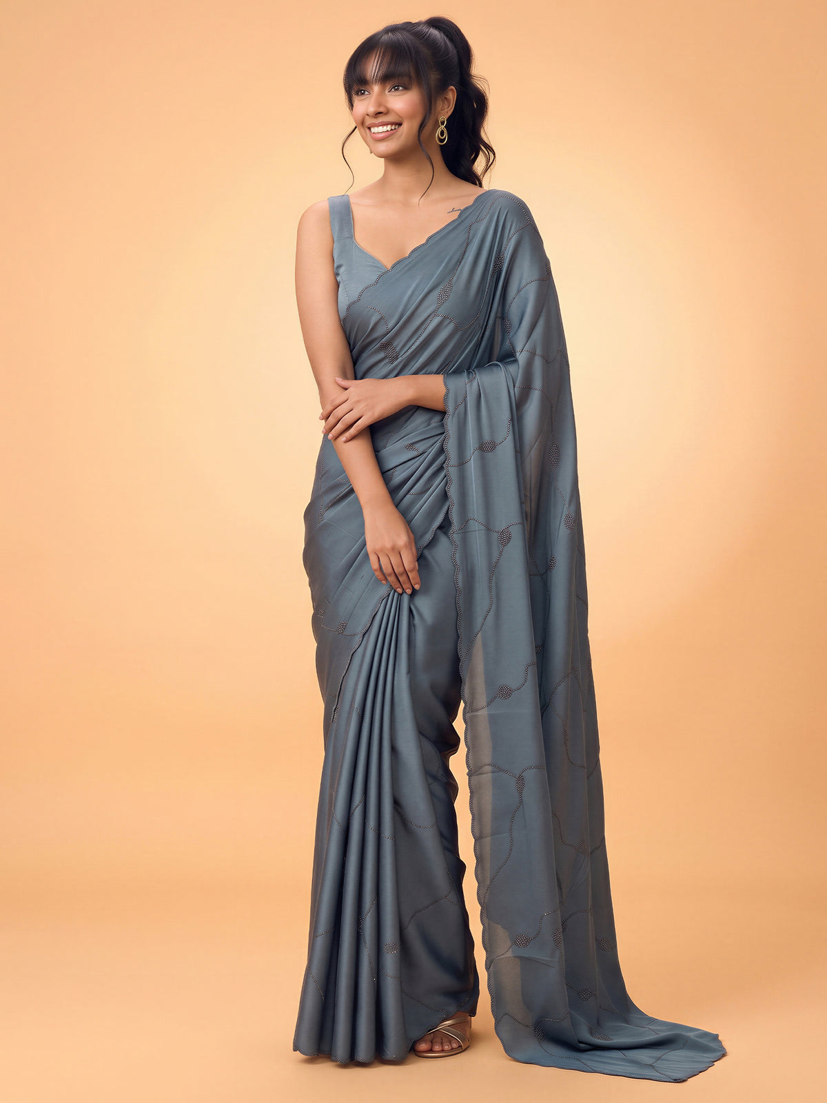Woman wearing teal blue satin silk saree with ornamented surface design and teal blue blouse