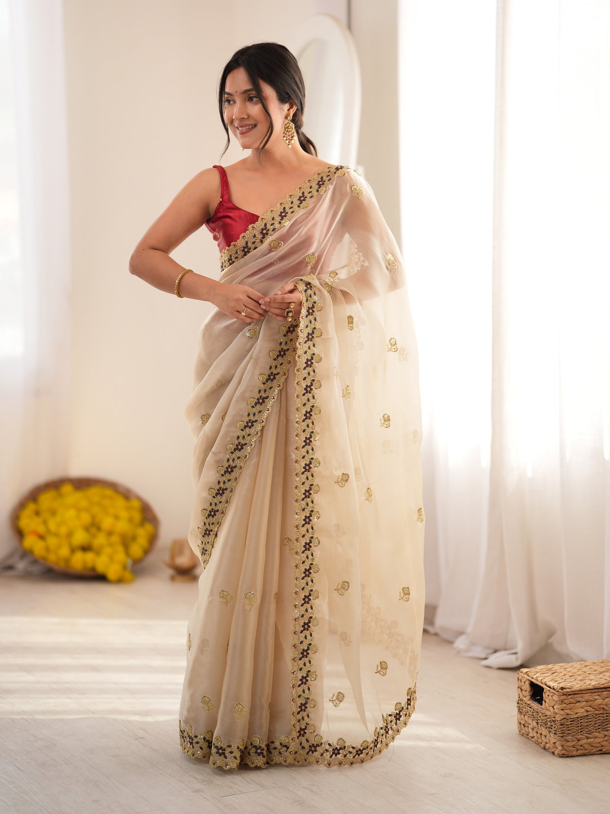 Woman wearing beige satin saree with ornamented surface design and red blouse
