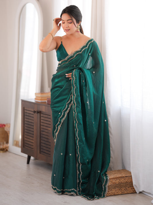 Woman wearing teal green satin silk saree with ornamented surface design and teal green blouse