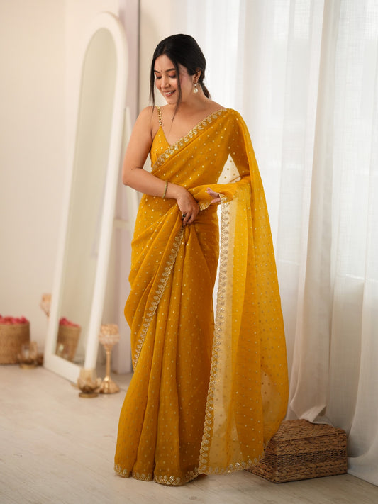 Woman wearing mustard georgette saree with zari butta (metallic motif) work and mustard blouse